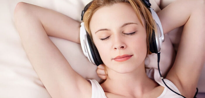 woman wearing headphones in bed listening to music to fall asleep