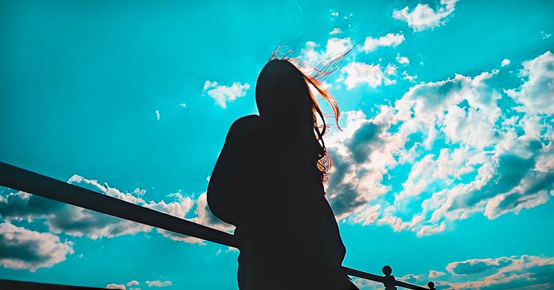silhouette of young woman against blue sky - illustrating the concept of a free spirit