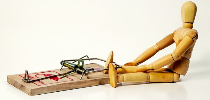 small wooden mannequin with foot trapped in mouse trap