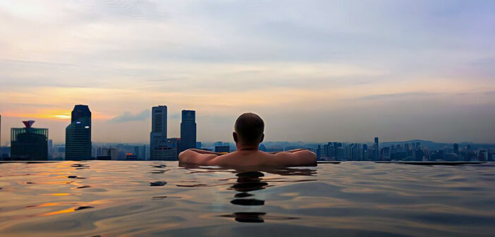 successful man swimming in rooftop pool