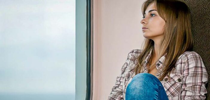 young woman sitting by train window showing signs of anticipatory anxiety