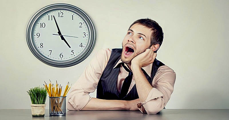 man at work watching clock indicating that he wants to make time go by faster