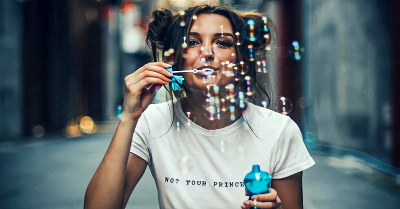 young woman enjoying life by blowing bubbles