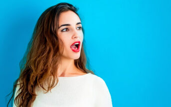 young woman with open mouth as if about to speak, isolated against blue background