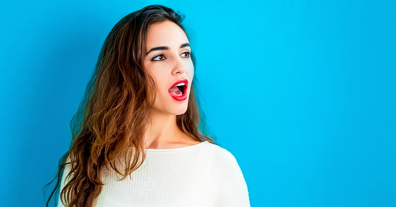 young woman with open mouth as if about to speak, isolated against blue background
