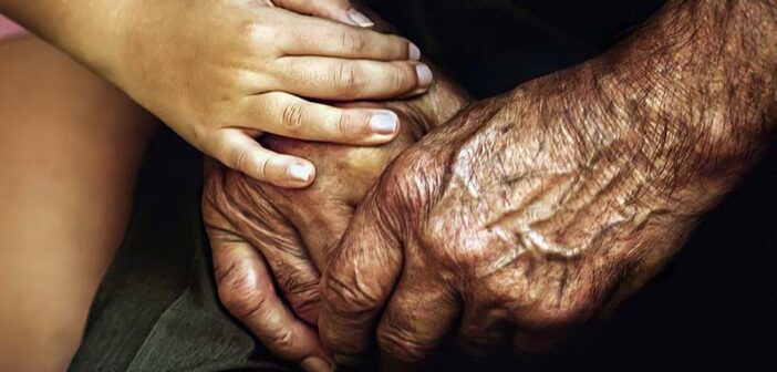 closeup of child holding elderly person's hands and showing them compassion