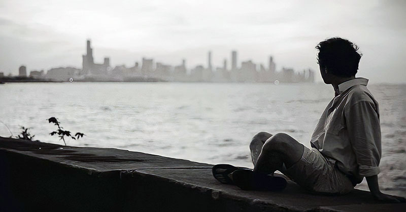 man looking across sea at city asking what is the purpose of life?