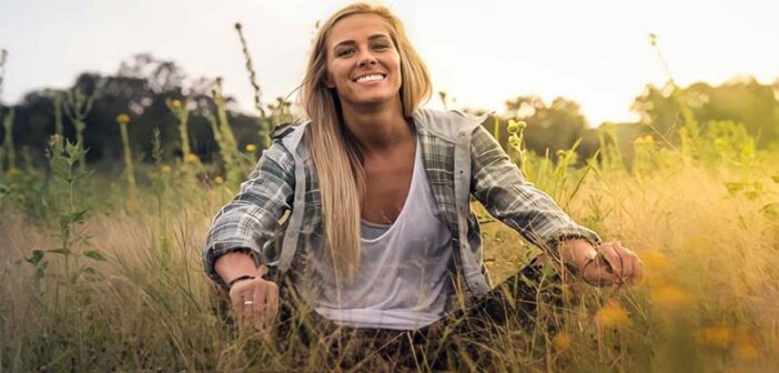 emotionally independent woman smiling sitting in grassy field