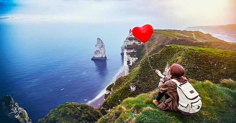 girl on cliff holding heart balloon illustrating that she's never been in a relationship or in love before