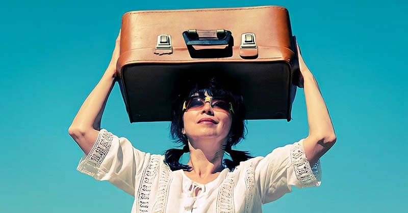 middle-aged woman holding suitcase above her heard illustrating leaving everything behind to start a new life
