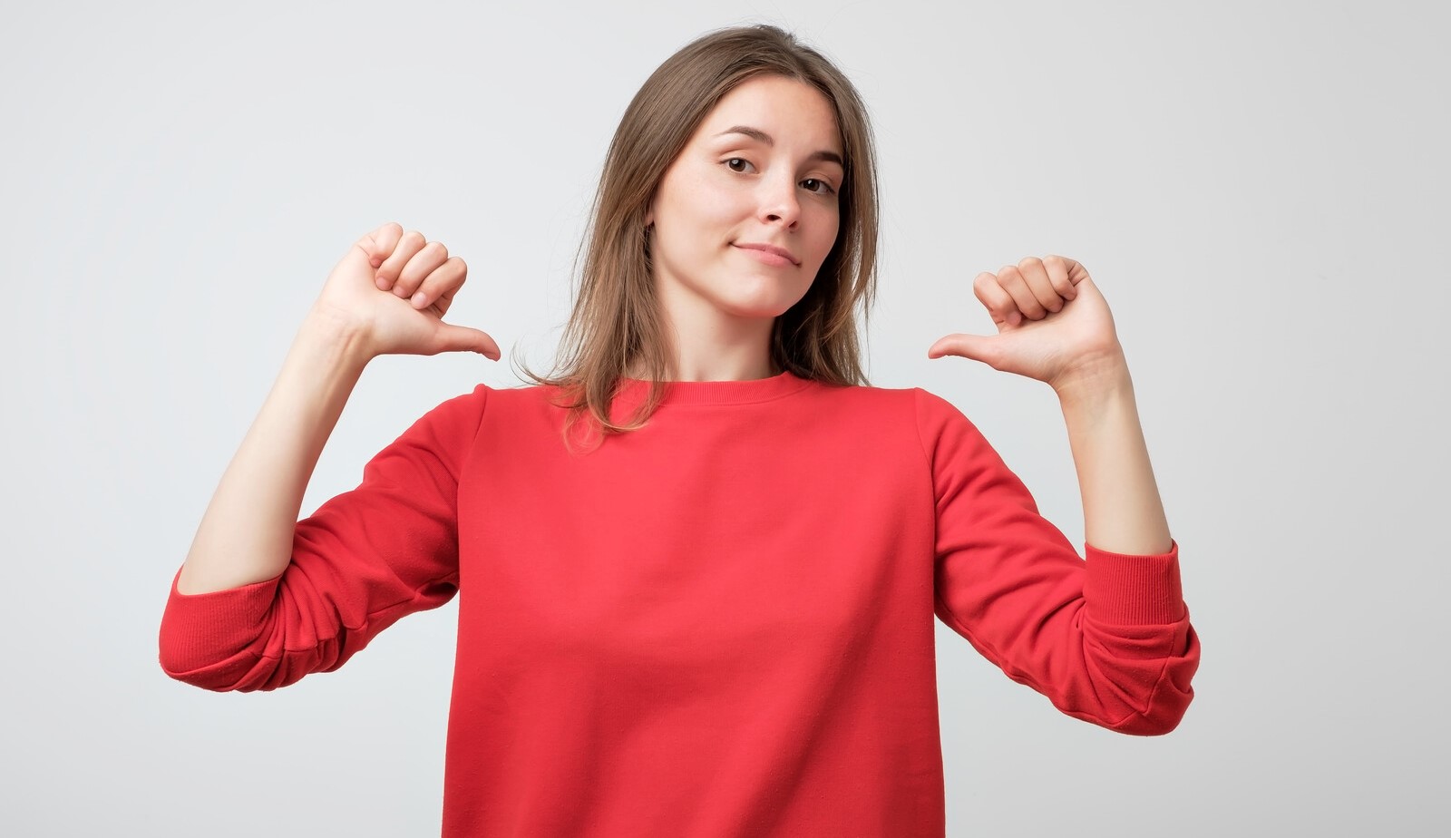 woman pointing both thumbs at herself