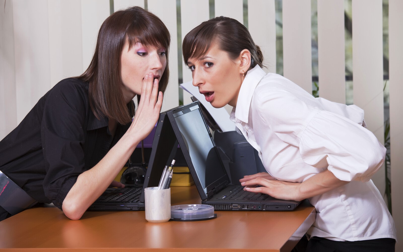 two women gossiping in an office setting