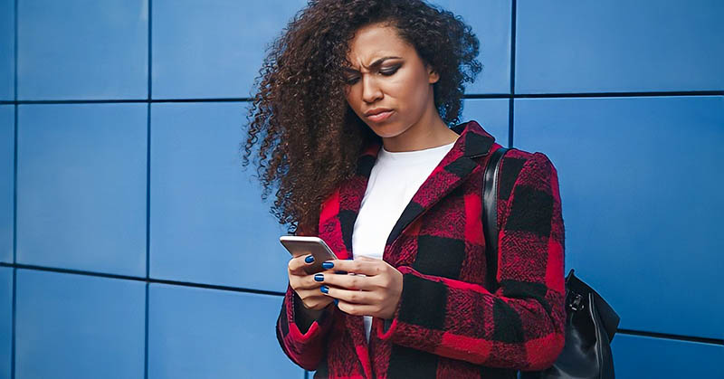 young woman looking at phone with confused expression illustrating the concept of breadcrumbing