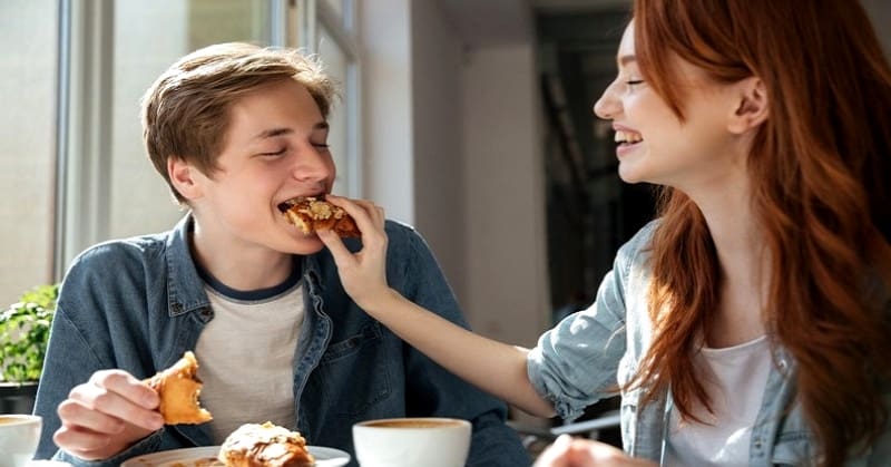 young woman feeding food to a man on a date