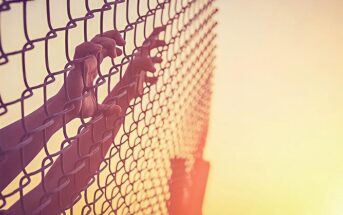 hands on chain link fence illustrating feeling trapped in life