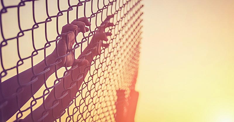 hands on chain link fence illustrating feeling trapped in life