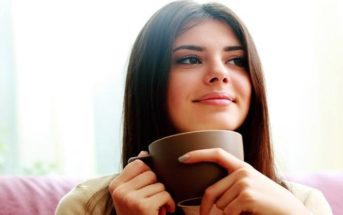 woman drinking coffee with smile on her face showing that she has become happy again
