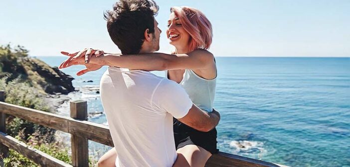 young couple smiling with ocean in the background illustrating infatuation versus love