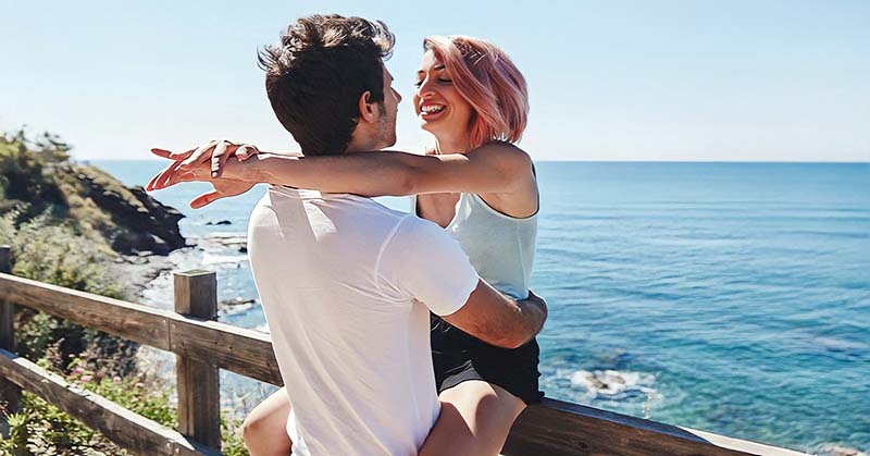 young couple smiling with ocean in the background illustrating infatuation versus love