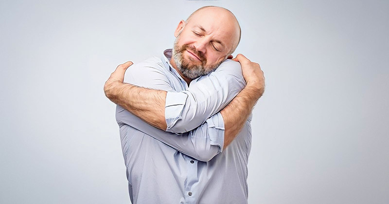 man hugging himself illustrating being kind to yourself