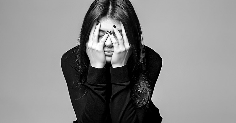 black and white image of young woman with hands across face illustrating that life is hard