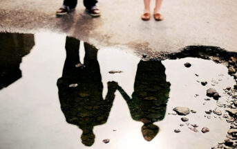 reflection in a puddle of couple holding hands illustrating a situationship