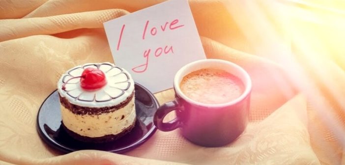 cake, cup of coffee and love note laid on bed illustrating surprising your girlfriend