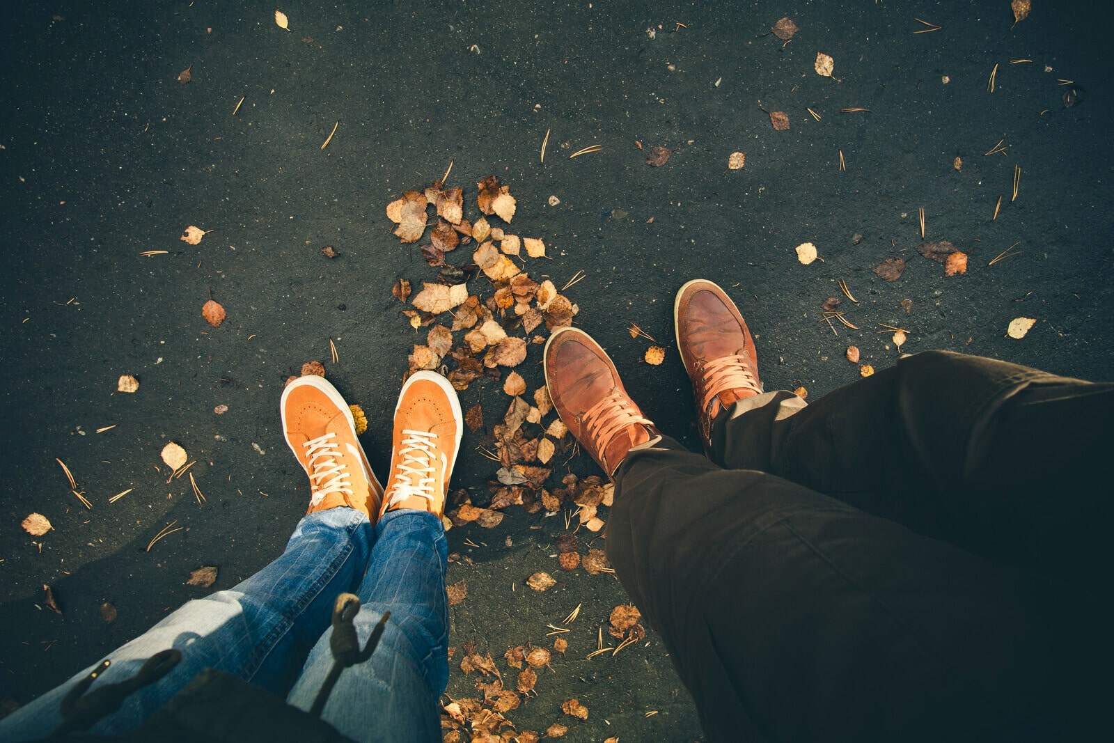 the feet of a man and woman as they walk on an autumn path