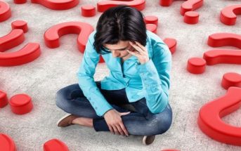 young anxious girl sitting on floor surrounded by question marks illustrating decision anxiety