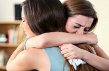 young woman hugging her crying friend and helping her through a breakup