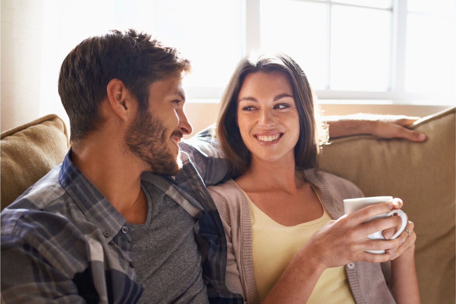 man and woman smiling while talking on the couch