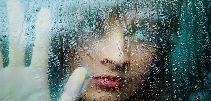 woman looking through rainy window having lost faith in humanity