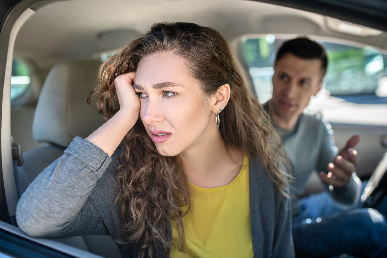 upset woman looking away from man while they sit in the car