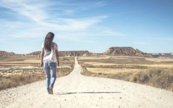 woman walking desert path into the horizon illustrating setting a goal
