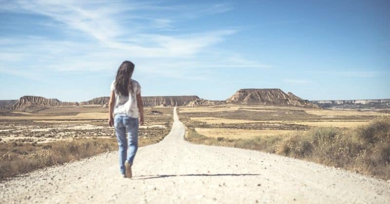 woman walking desert path into the horizon illustrating setting a goal
