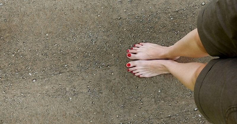 woman's bare feet on stony ground