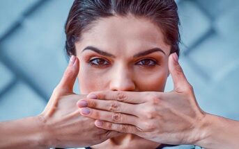 Woman with her hands over her mouth as she tries to stop saying sorry so much