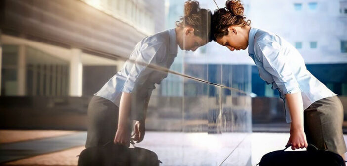 businesswoman leaning head against glass building illustrating burnout and its symptoms