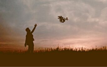 silhouette of person throwing flowers into the sky, thus letting go of the past