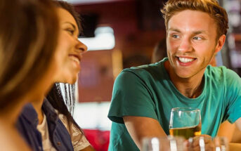 a guy and two girls making small talk in a bar