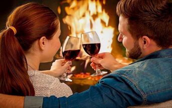 a couple with wine in front of a fire enjoying a date night at home