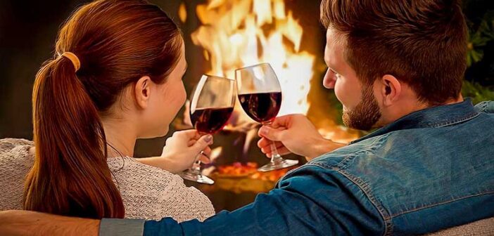 a couple with wine in front of a fire enjoying a date night at home