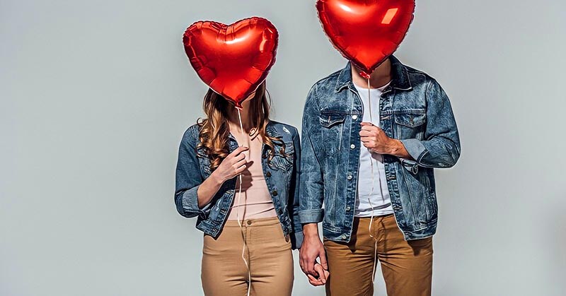 boyfriend and girlfriend with faces concealed by heart shaped balloons