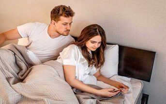 boyfriend looking over girlfriend's shoulder at her text messages - illustrating a partner with trust issues