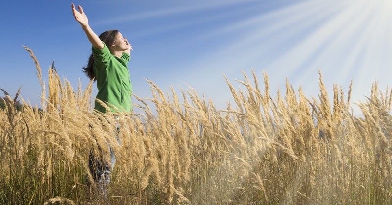 woman with arms in the air facing toward sun - illustrating spiritual goals