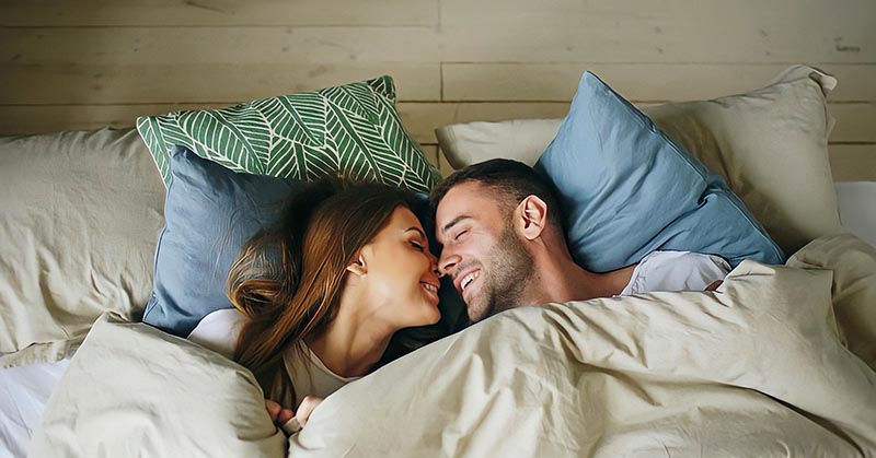 happy man and woman in bed - illustrating what a man wants in a woman