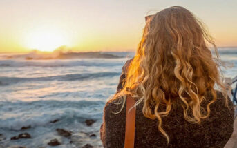 woman looking at sunrise over the ocean illustrating hope