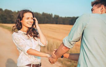 happy young woman pulling on hand of boyfriend in a field - illustrating complimenting a guy