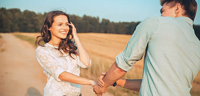 happy young woman pulling on hand of boyfriend in a field - illustrating complimenting a guy