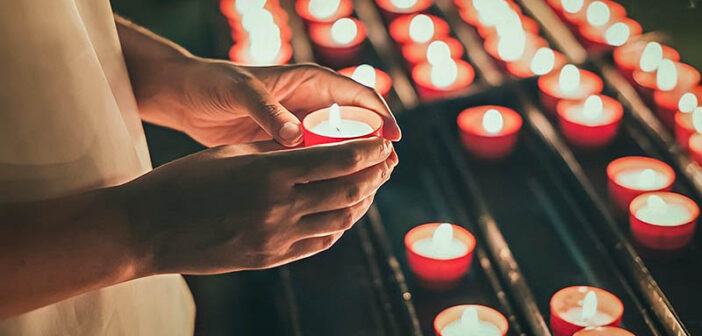 person lighting a candle for a dead loved one
